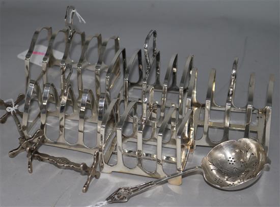 Five silver toast racks, a pair of silver knife rests and a tea strainer